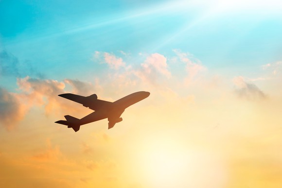 A plane taking off against a colorful sunrise