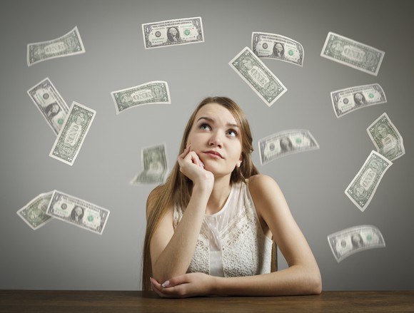 A young woman staring at falling dollar bills.