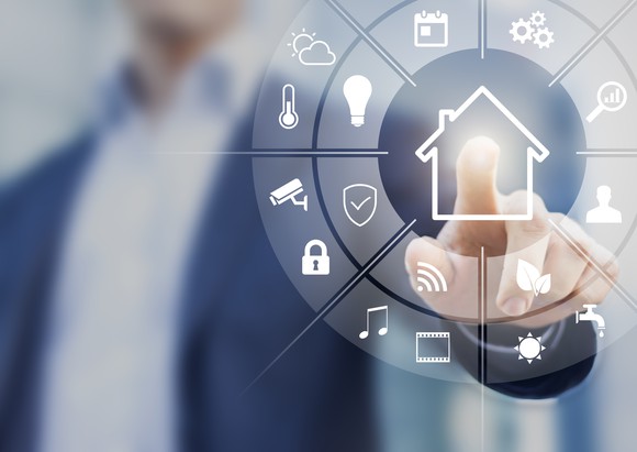 A man presses the "home" icon on a dial representing the smart home concept.