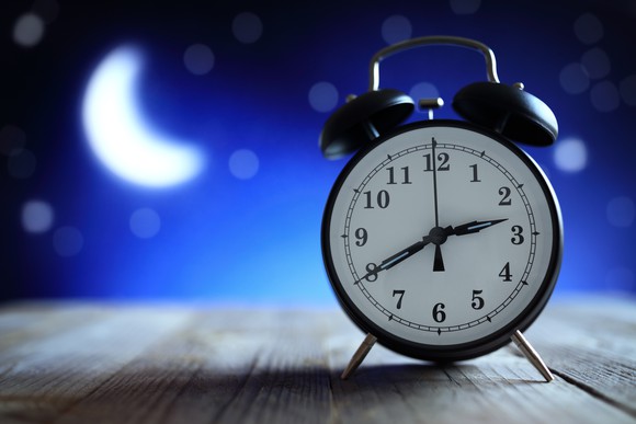 An alarm clock with the moon and stars in the background.
