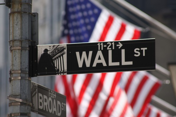 Wall St sign with American flag in the background