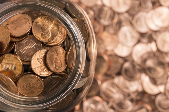 A jar of copper pennies surrounded by pennies.