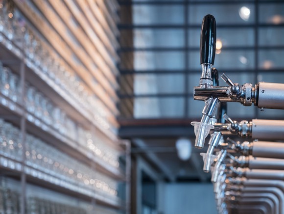 Line of chrome and silver beer taps in an industrial style bar.
