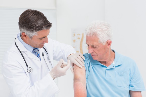 An elderly man receives an injection from a doctor.