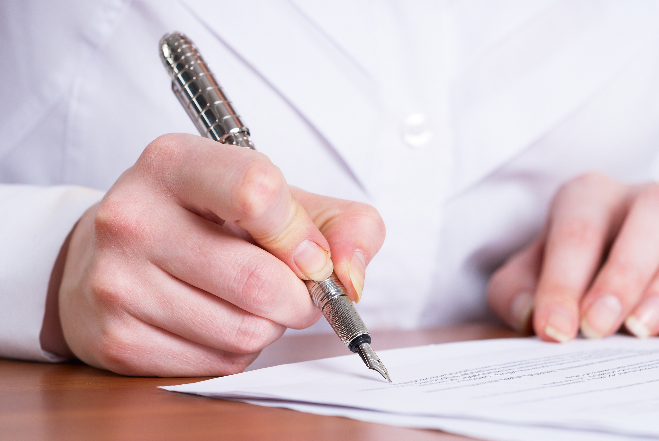 A man signs a piece of paper with a fancy pen.