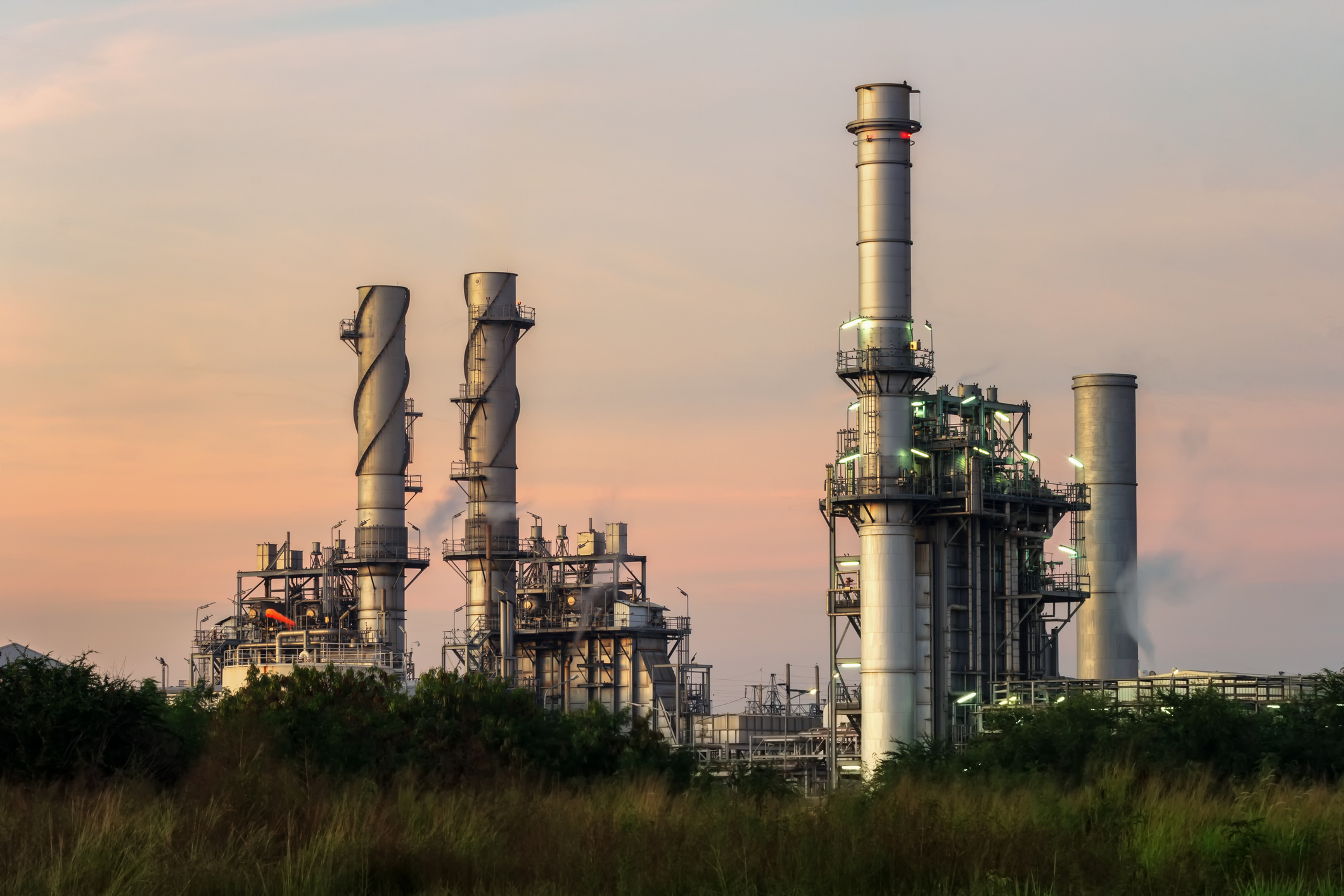 A power plant's smokestacks are framed against an evening sky.