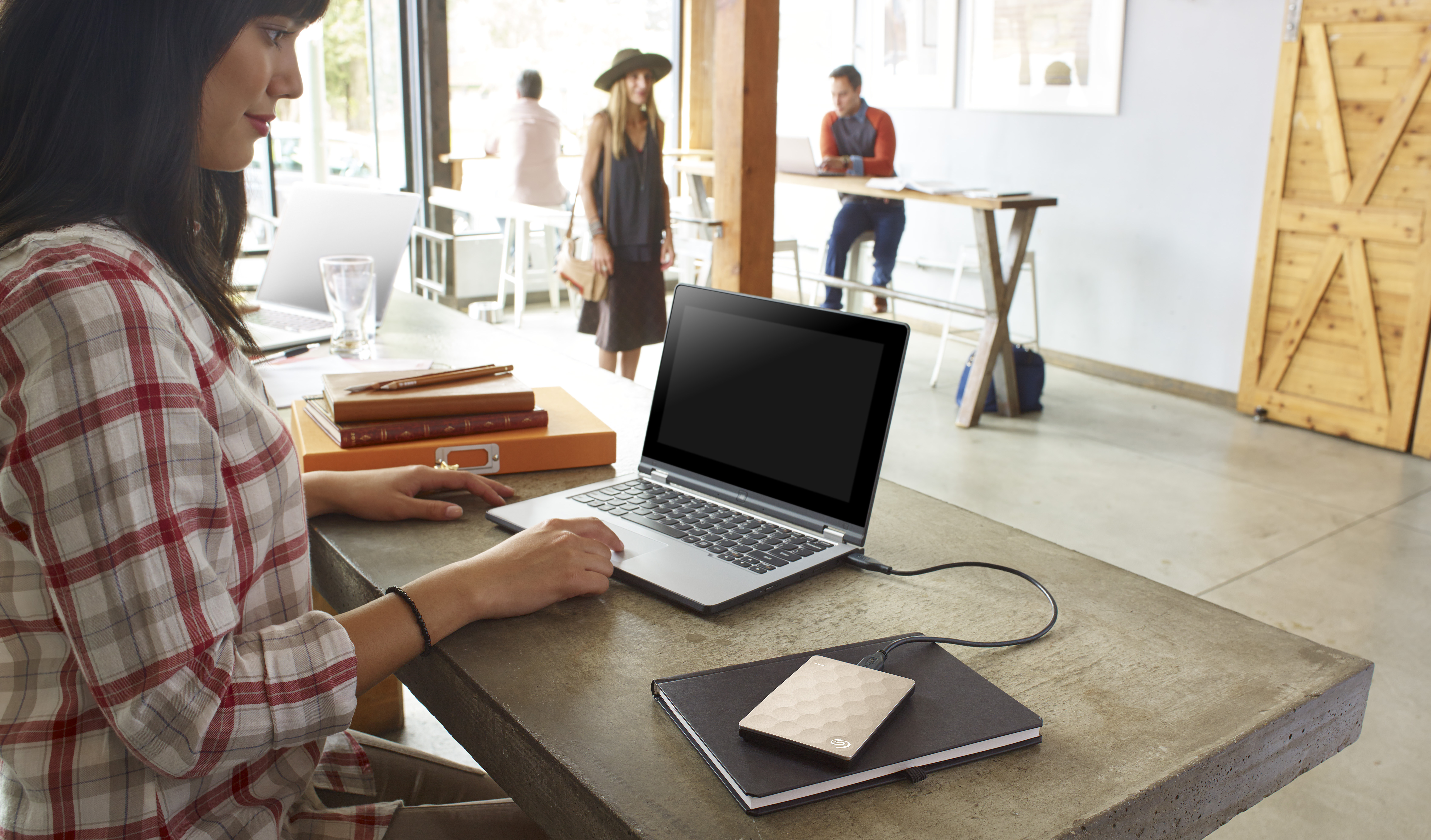 Woman using a portable hard drive and laptop