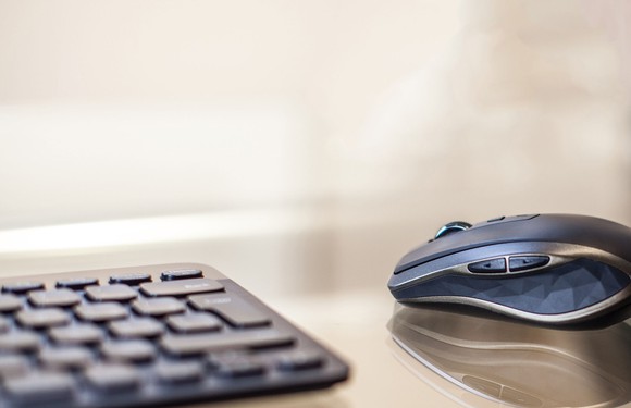 Logitech's MX Anywhere wireless mouse next to a keyboard.