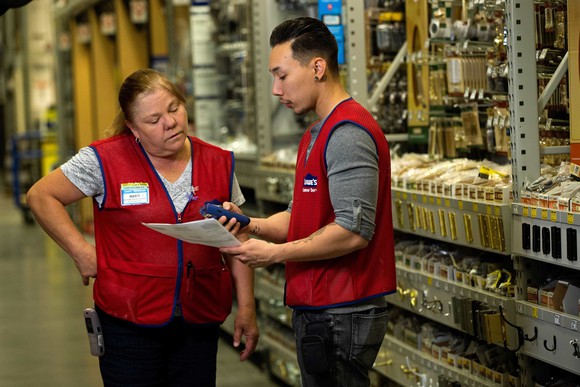 Two Lowe's employees discussing their tasks with each other.