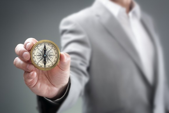 A man holds a compass out toward the camera.