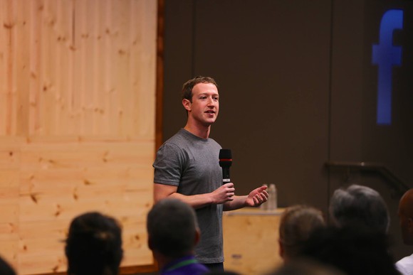 Facebook CEO Mark Zuckerberg holding a microphone addressing an audience.