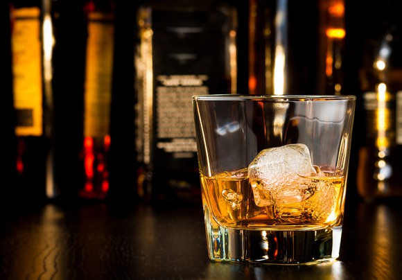 Glass of whiskey with bottles in the background.