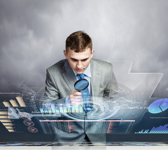 business man looking with magnifying glass at data