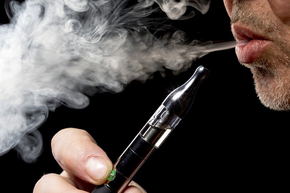 An electronic cigarette user exhaling vapor.