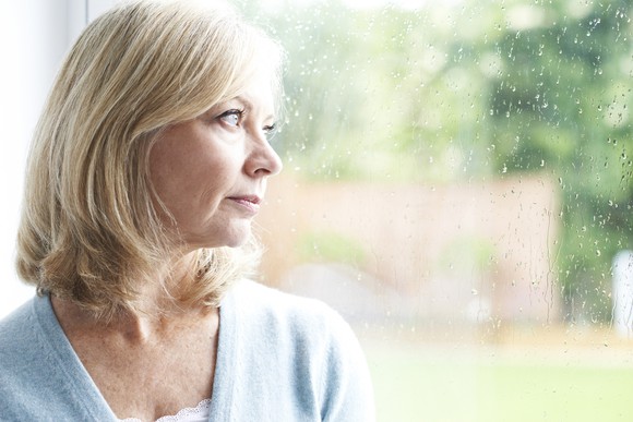 Middle-aged woman looking out the window on a rainy day