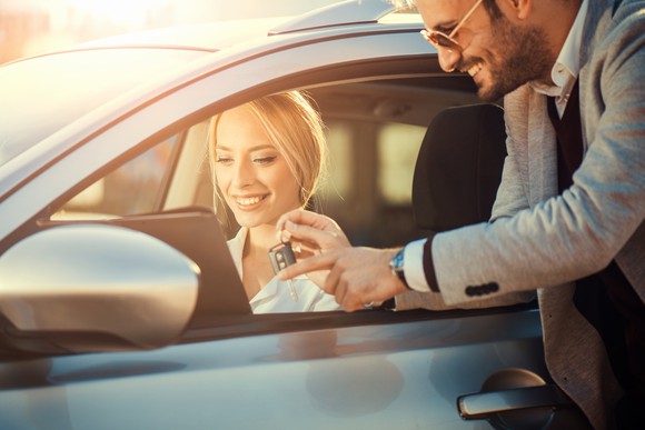 A woman receiving the keys to a rental car