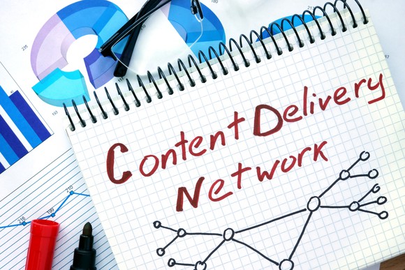 Notepad on top of chart printouts, with the words "Content Delivery Network" written by hand in red ink.