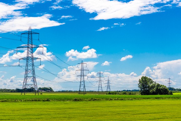 A row of transmission pylons stretching into the horizon against blue skies.
