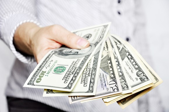 man holding bills fanned out in front of him