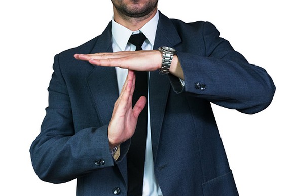 man in a suit creating a "T" with his hands