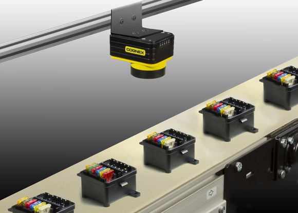 A Cognex machine vision system mounted above conveyor belt with various objects.