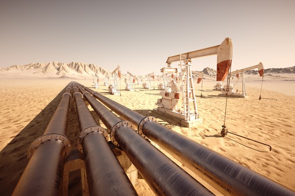 Oil pump jacks and pipelines in a desert landscape.