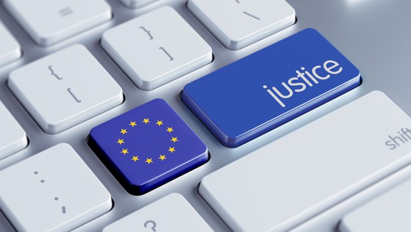 Off-white computer keyboard where the blue "enter" key contains the word "justice" instead and the apostrophe key has been replaced by a European Union flag.