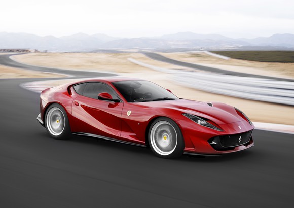 A red Ferrari 812 Superfast sports car at speed on a winding road.