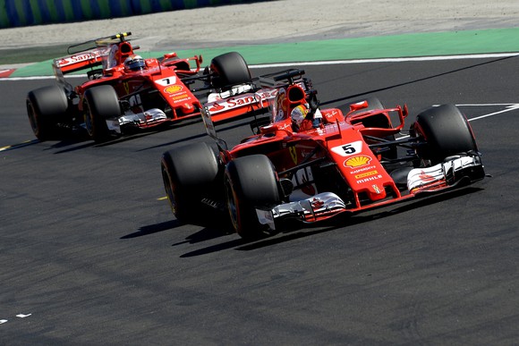 Two red Ferrari Formula 1 racing cars, numbered 5 and 7, on track at the Hungarian Grand Prix.