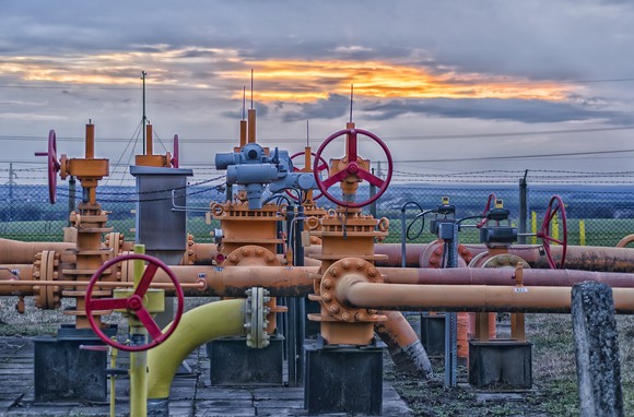 A natural-gas field with pipelines and valves at sunset