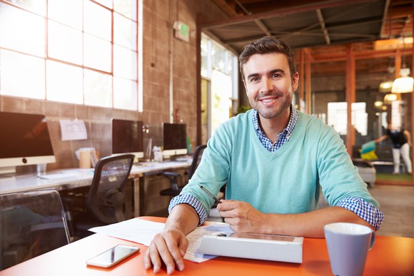 30-something man sitting at a table in an office setting