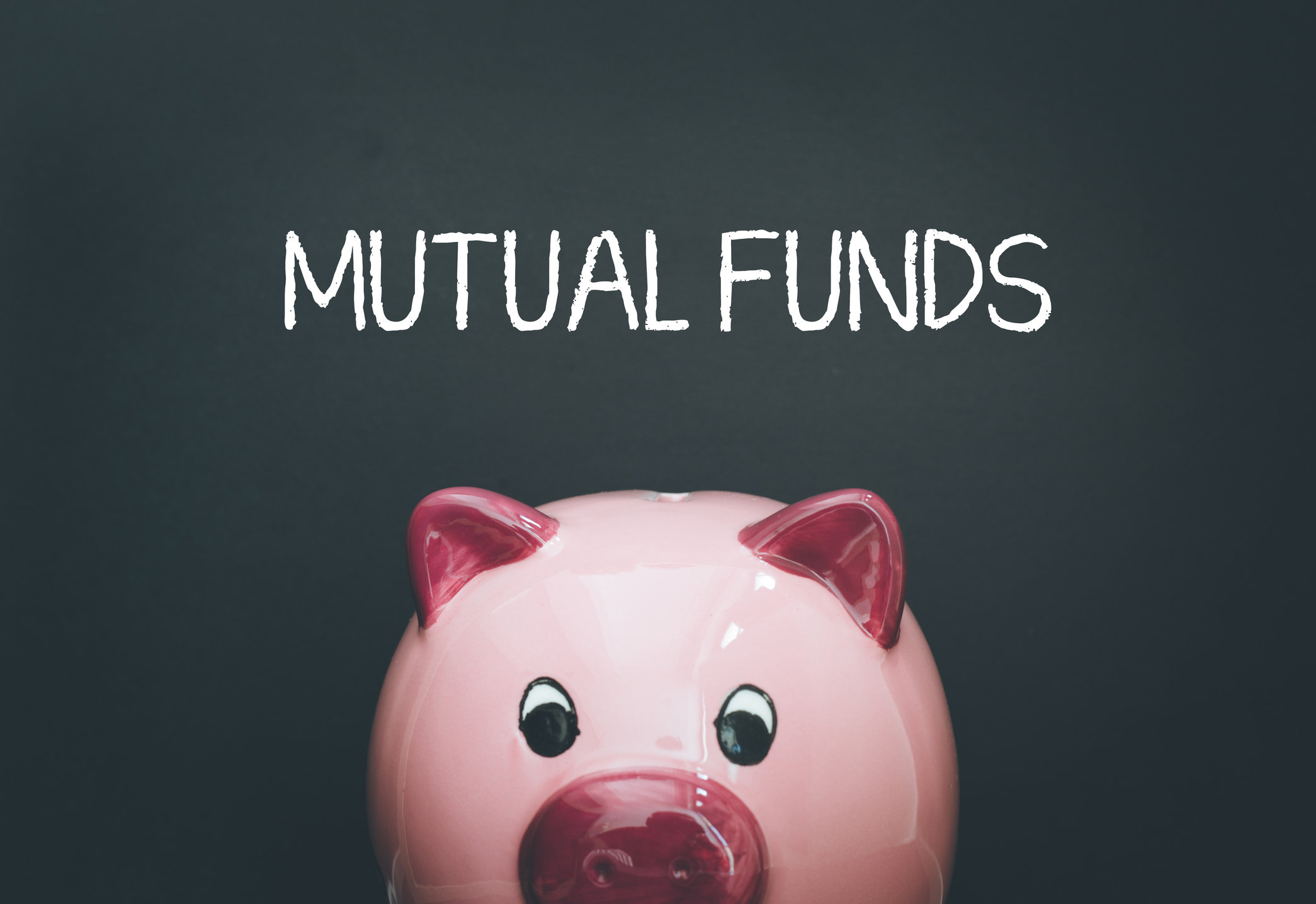 pink piggy bank in front of blackboard on which is written "mutual funds"