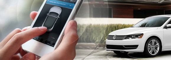 A white car on the right. On the left, hands holding a smartphone that is displaying information about the car.