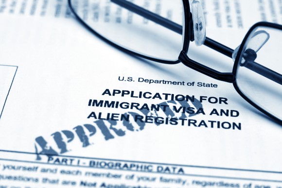 A pair of glasses sits on an approved application for immigration.