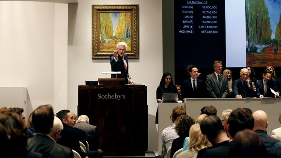 Auctioneer at a Sotheby's podium selling a piece of Impressionist art at a live auction.