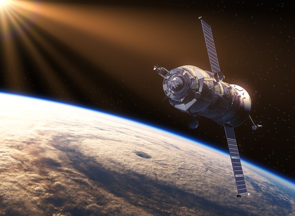 A satellite in space over the Earth, lit up by the Sun.