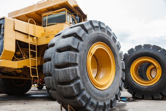 Large yellow construction truck with a closeup of a giant tire.