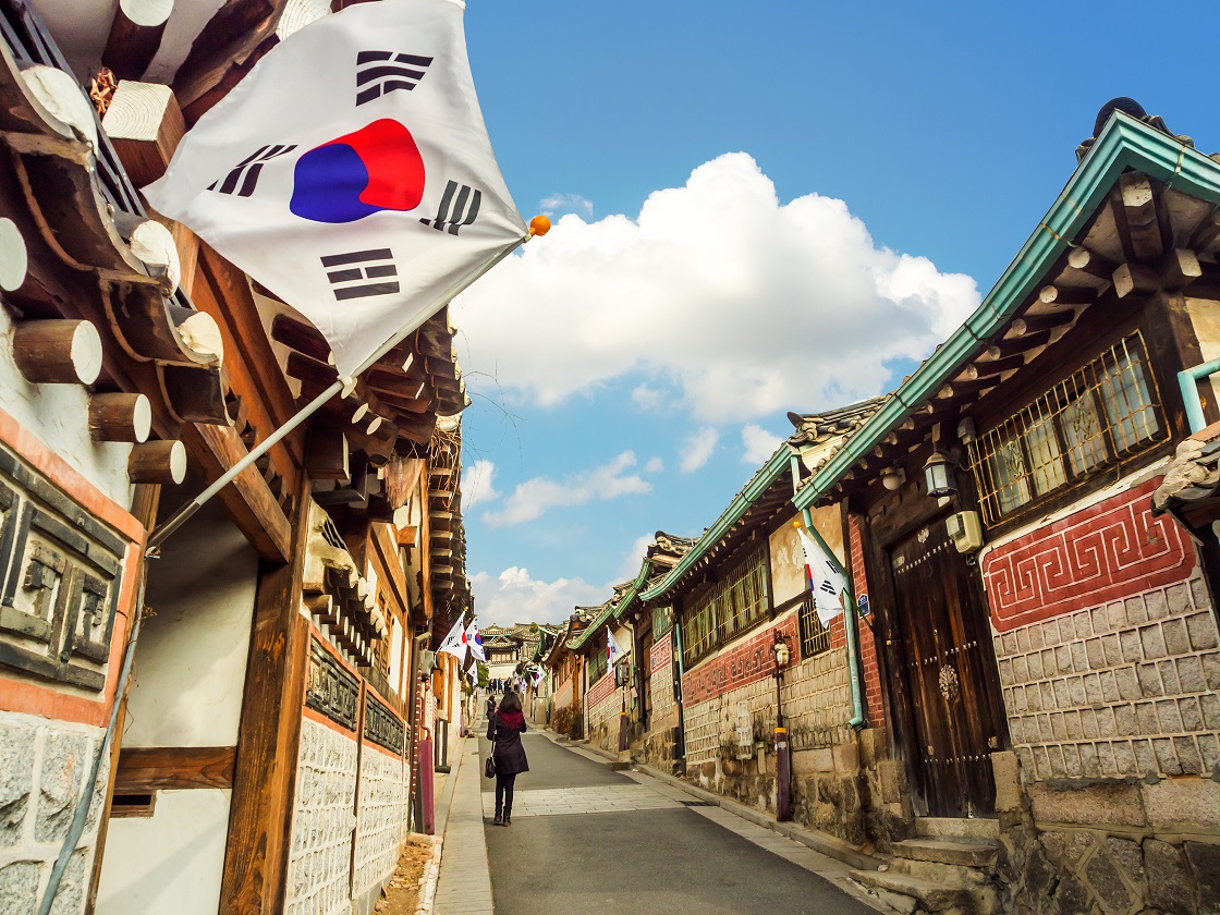 South Korean flag flying over a small street with buildings.