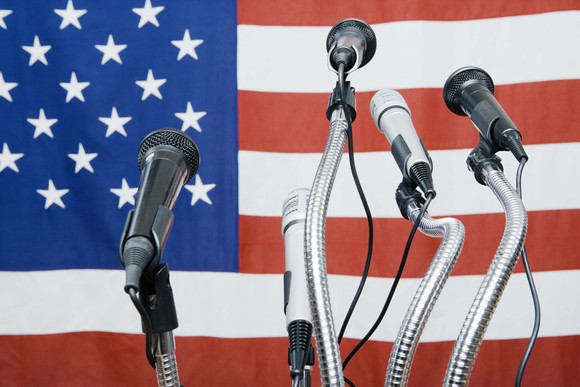 Bunch of microphones in front of a US flag