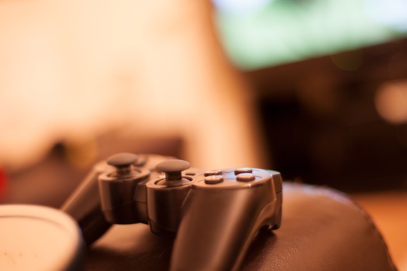 Video game controller on a couch with a TV in the background.