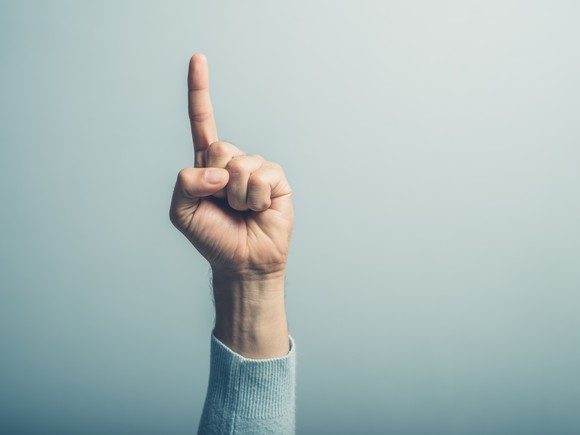 Finger pointing up against blue background