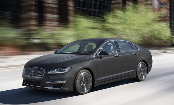 A 2017 Lincoln MKZ in dark gray on a wooded road.