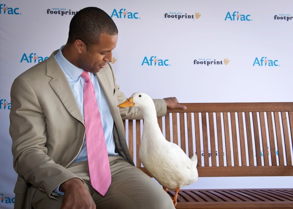 Duck with man in a suit on bench.