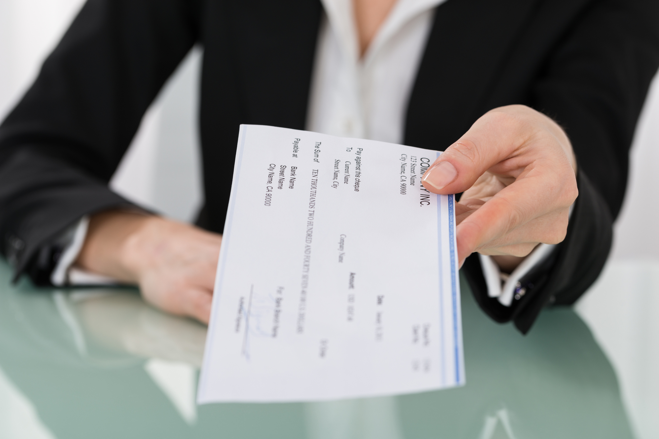 A professional woman handing over a paycheck.