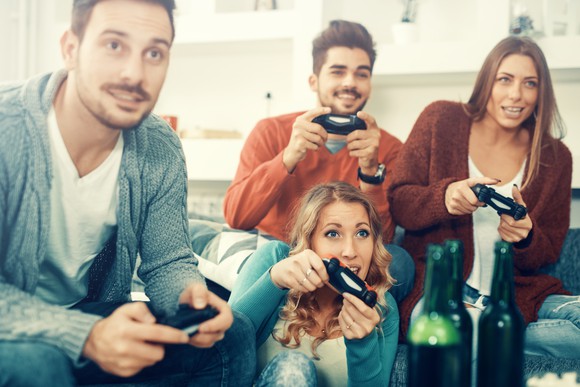 Two men and two women in a home playing video games.