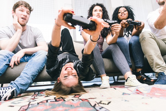 A group of young people sitting on a couch enjoying playing video games together.