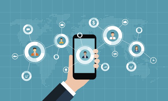 animation of hand holding cell phone with connection to people all over the a map of the world in the background.