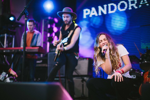 A Pandora concert stage with keyboardist, guitarist, and singer.