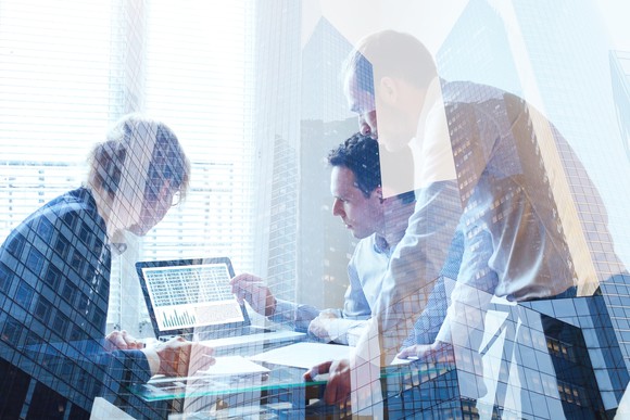 Three people working around a computer