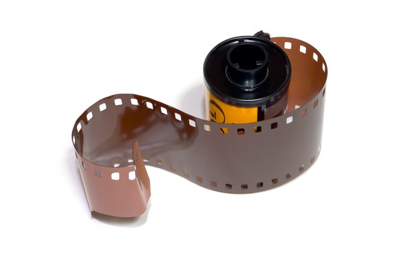 35 mm film roll with a few inches of film pulled out of the container.